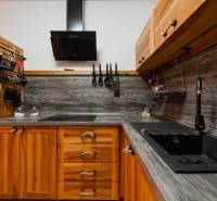 A kitchen in a 2-room apartment with wooden cabinets and a dark countertop.