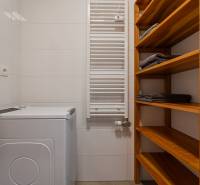 Washing machine, wooden shelves and ladder radiator in the bathroom of a 2-room apartment.