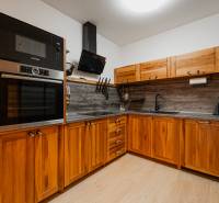A kitchen unit with wooden cabinets and a floor with a wooden decor in a 2-room apartment.