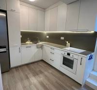 A kitchen in a 3-room apartment with built-in appliances and a floor with a wooden decor.