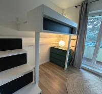 Interior of a 3-room apartment with a raised bed, wooden decor flooring, and a terrace.