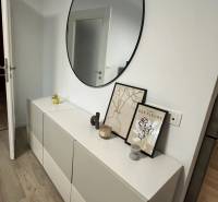 A modern sideboard with decorations and a round mirror in a 3-room apartment.