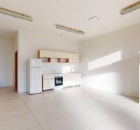 Interior of commercial space with a kitchenette, tiles, and white furniture.