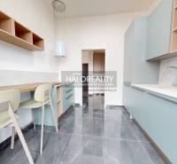 A kitchen with a bar counter, light cabinets, and a gray floor in offices.