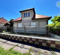 A family house in Levice with a metal fence and a sloped roof on a sunny plot.