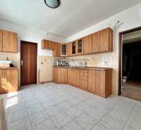 A kitchen in a family house with wooden cabinets and ceramic tiles.