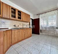 A kitchen with light tiles, wooden cabinets, and ceramic tiles in a family house.