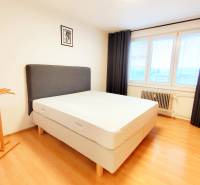 A bedroom with a bed, black curtain, and wood-patterned flooring in a 3-room apartment.