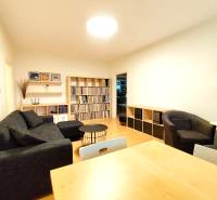 Living room in a 3-room apartment with a sofa, armchairs, shelves, and a wooden decor floor.