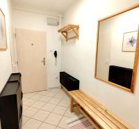 A hallway in a 3-room apartment with tiles, a wooden bench, and a mirror on the wall.