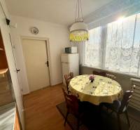 Dining area in a 3-room apartment with a round table and wooden decor flooring.