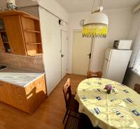 A kitchen in a 3-room apartment, a floor with a wooden decor, a dining table, cabinets, a refrigerator.