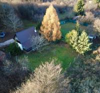 A cottage in Štitáre surrounded by greenery and trees, with a car on the driveway.