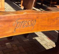 A wooden bench with an engraved inscription in front of the commercial premises on Park and Main Street, Veľké Ludince.