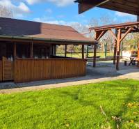 Garden with a gazebo near commercial premises in Veľké Ludince, park and main road.
