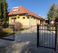 Courtyard with a gate, café, and building with commercial spaces in Veľké Ludince.