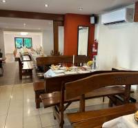 Interior of commercial premises with wooden benches, set tables, and air conditioning.