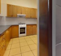 A kitchen in a family house with wooden cabinets and a tiled floor.