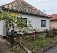 A family house in Hokovce with a ceramic roof and fencing, surrounded by greenery.