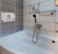 A bathroom in a family house with floral tiles and a bathtub.