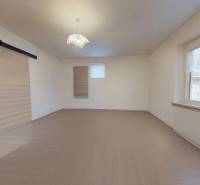 The interior of a room in a family house with a wood-patterned floor and a glass window.