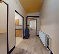 Hallway in a family house with a radiator and a view into the kitchen and room.