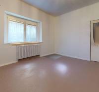 White wall, window with radiator, and door in a room in a family house.