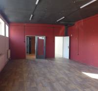 Red walls, wood-patterned floor, and windows in an industrial space of warehouses and halls.