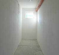 A narrow corridor with a bright window and orange piping, warehouses and halls.