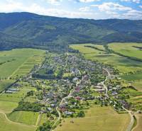 Aerial view of agricultural and forest land around Hertník surrounded by forests.
