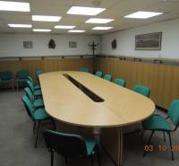 A conference room with a long wooden table and green chairs in an office.