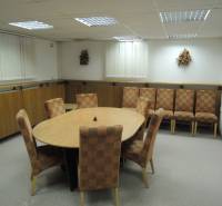 Offices with an oval table and patterned chairs on a carpet.