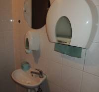 Offices with a sink, a round mirror, and a paper towel dispenser.