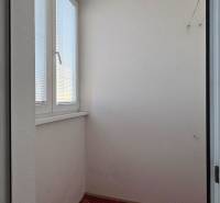 A small room with a red carpet and a window in a studio apartment.