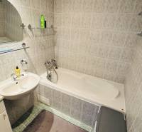 A bathroom with a bathtub and a sink in a 4-room apartment, tiles in light tones.