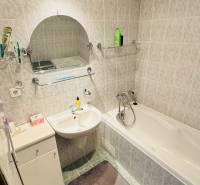 A bathroom in a 4-room apartment with a bathtub, sink, and tiles with a light decor.