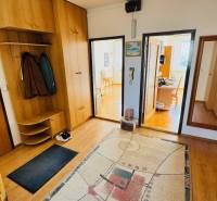 Entrance hall of a 4-room apartment with wood-patterned flooring, carpet, and wooden furniture.