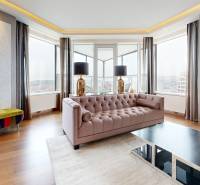 Living room with wood-patterned flooring, a sofa, and large windows in a three-room apartment.