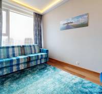 A bright living room with a blue carpet and sofa, and a wooden decor floor.