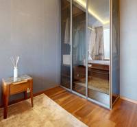 A bedroom in a three-room apartment with a wood-patterned floor, a built-in wardrobe, and a desk.