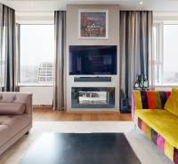 Living room in a 3-room apartment with colorful sofas, TV, and wood-decor flooring.