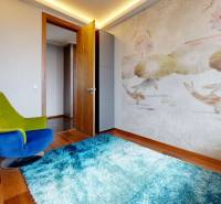 A room in a 3-room apartment with an armchair, wall texture, and a floor with a wooden decor.