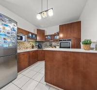 A kitchen in a 2-room apartment with brown cabinets and colorful mosaic tiles.