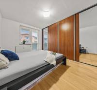 A bedroom with a bed, built-in wardrobe, and wooden decor flooring in a 2-room apartment.
