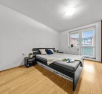 Bedroom in a 2-room apartment with a bed, nightstands, and a floor with a wood decor.
