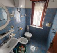 A bathroom with blue tiles, a sink, and a toilet in a 3-room apartment.