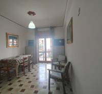 Dining room in a two-room apartment with a tiled floor and simple furnishings.