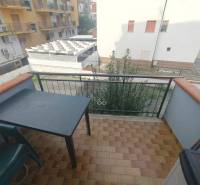 A balcony with a table and a chair in a 2-room apartment with a view of the street in Scalea.