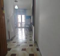 A narrow hallway in a 2-room apartment, light floor, table by the window.