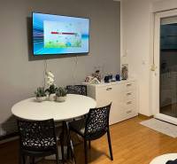 Dining area in a 3-room apartment with a wood-patterned floor and a television.